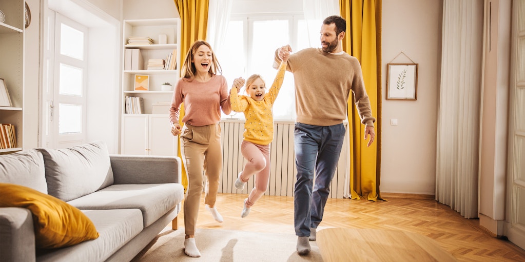 Parents picking up child in sunny room