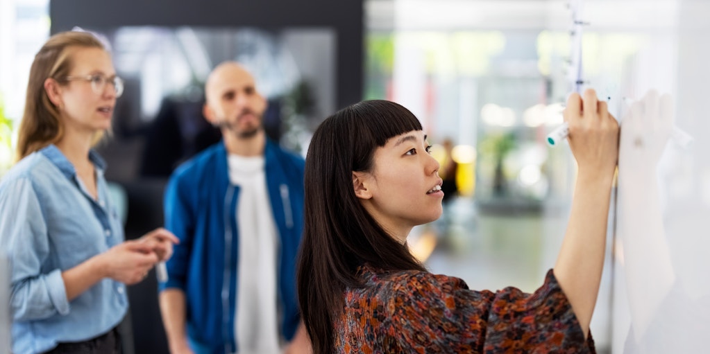 Three colleagues working together at a whiteboard