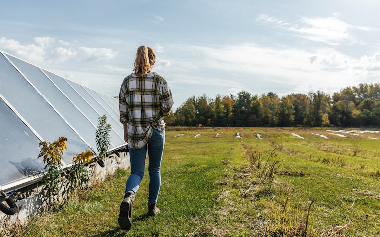 Farmer walking past greenhouse towards field