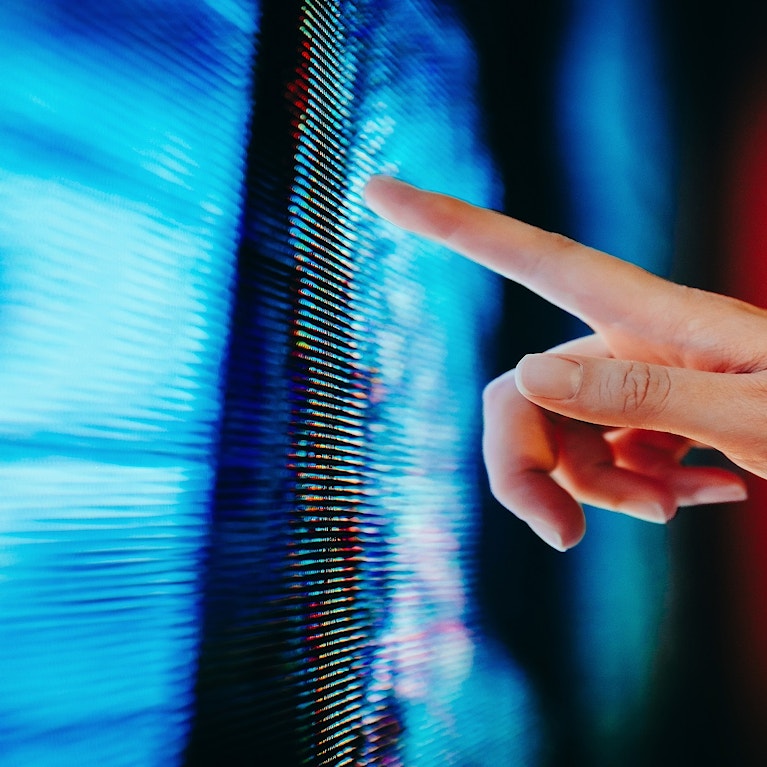 Close up of woman's hand touching illuminated and multi-coloured LED display screen