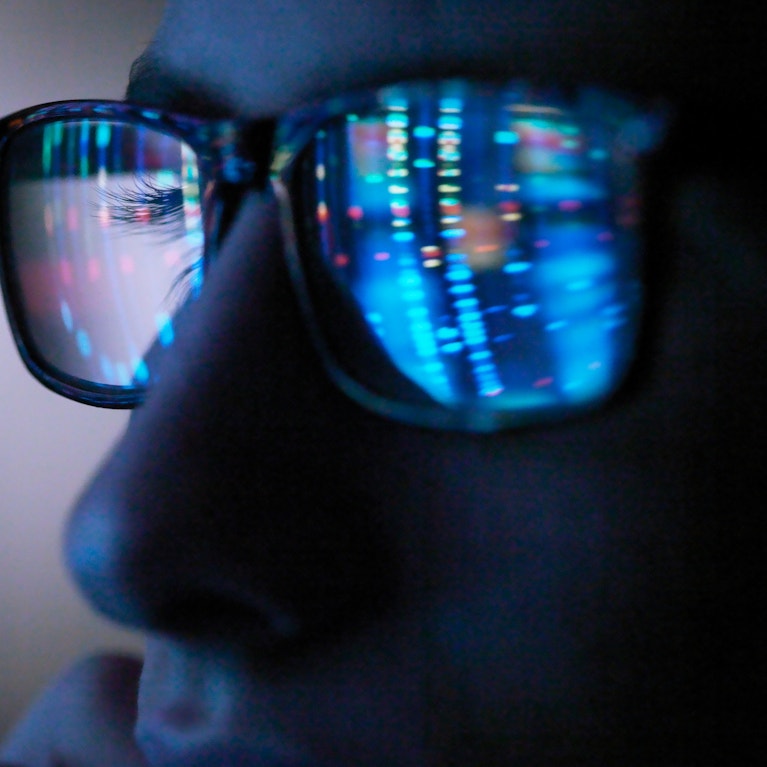 Genetic research, computer screen reflection in spectacles of DNA profile, close up of face