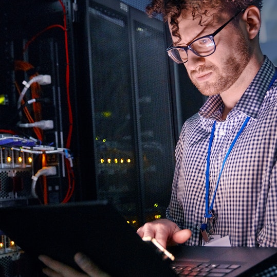 IT technician in server room with laptop