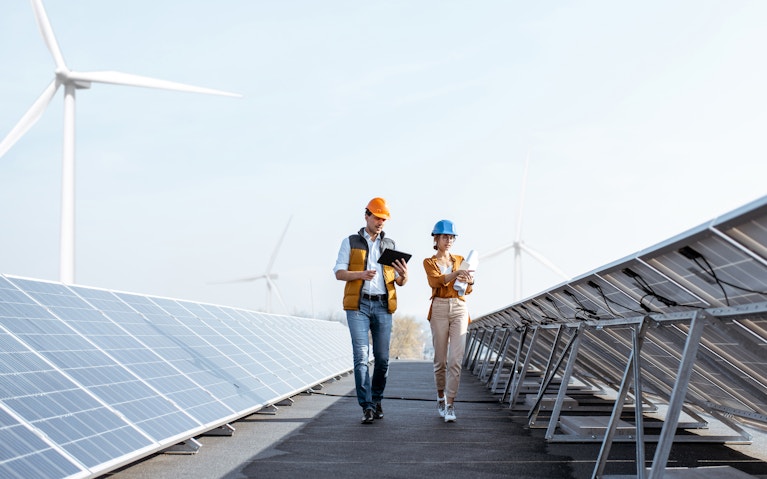 Two people walking through solar panels.