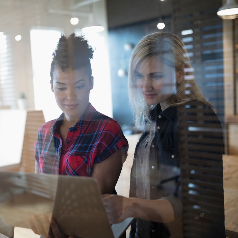 Creative businesswomen standing, working at laptop in office