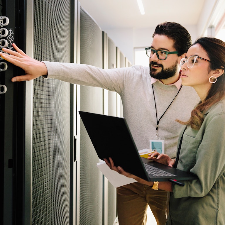 IT technicians examining equipment in network server room