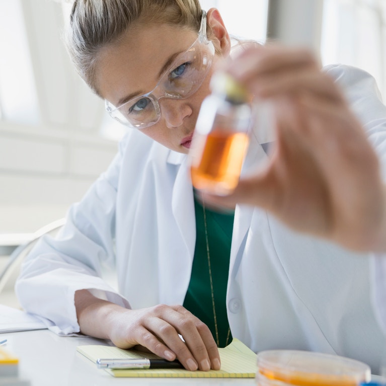 Scientist examining liquid in jar