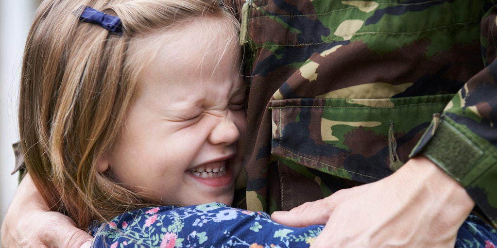 Young girl hugging a member of the armed forces