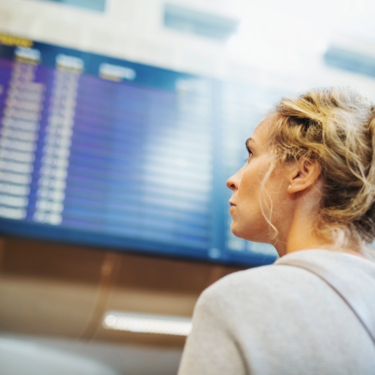 Air traveller looking at airport departure and arrivals information board