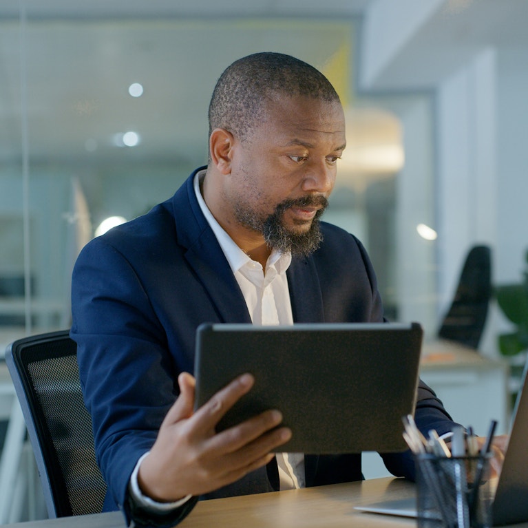 Laptop, tablet and businessman with trading research for a stock market financial investment at office desk.