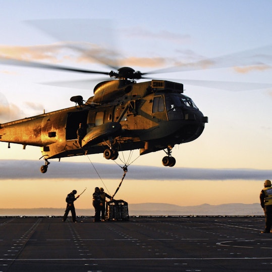 Military helicopter against sunset background.
