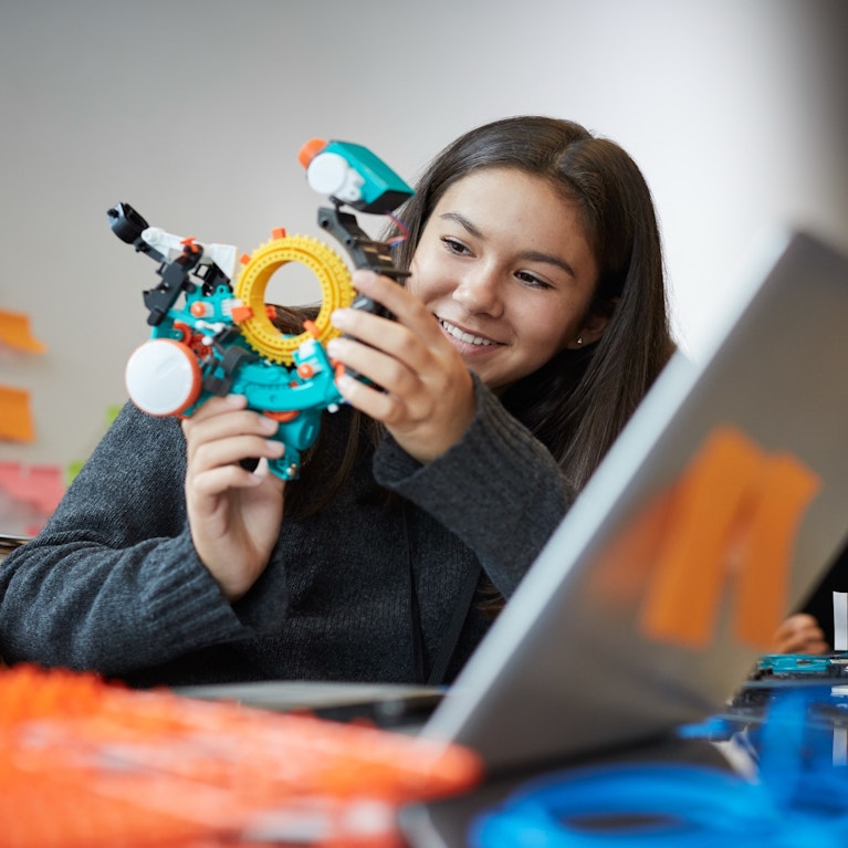 Smiling girl experimenting with model in science classroom.