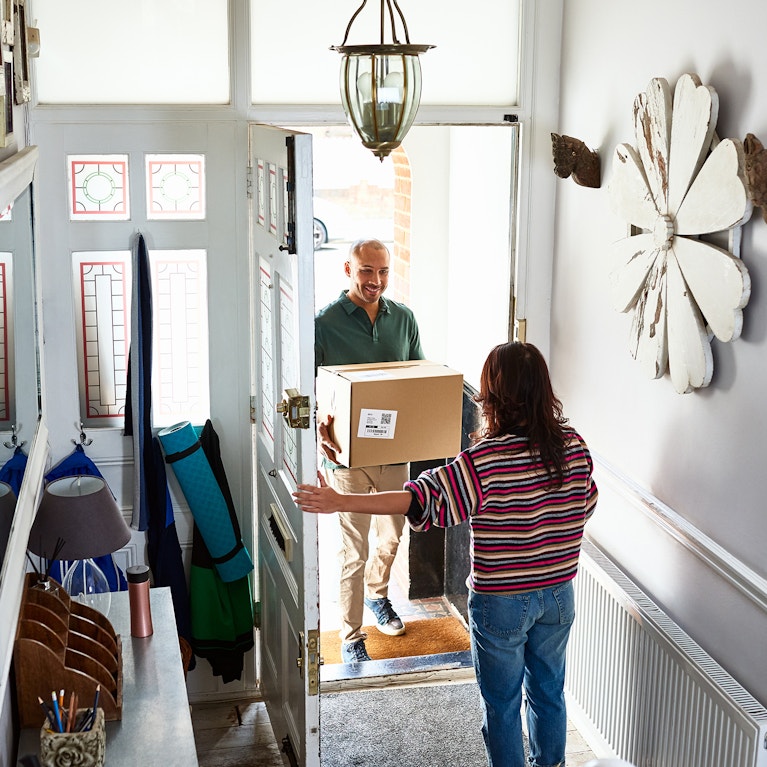 Delivery man giving parcel to woman in hallway