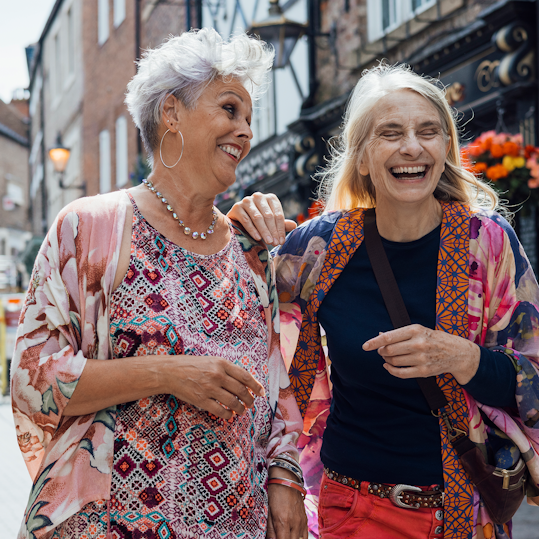 Two female friends walking side-by-side in a high street